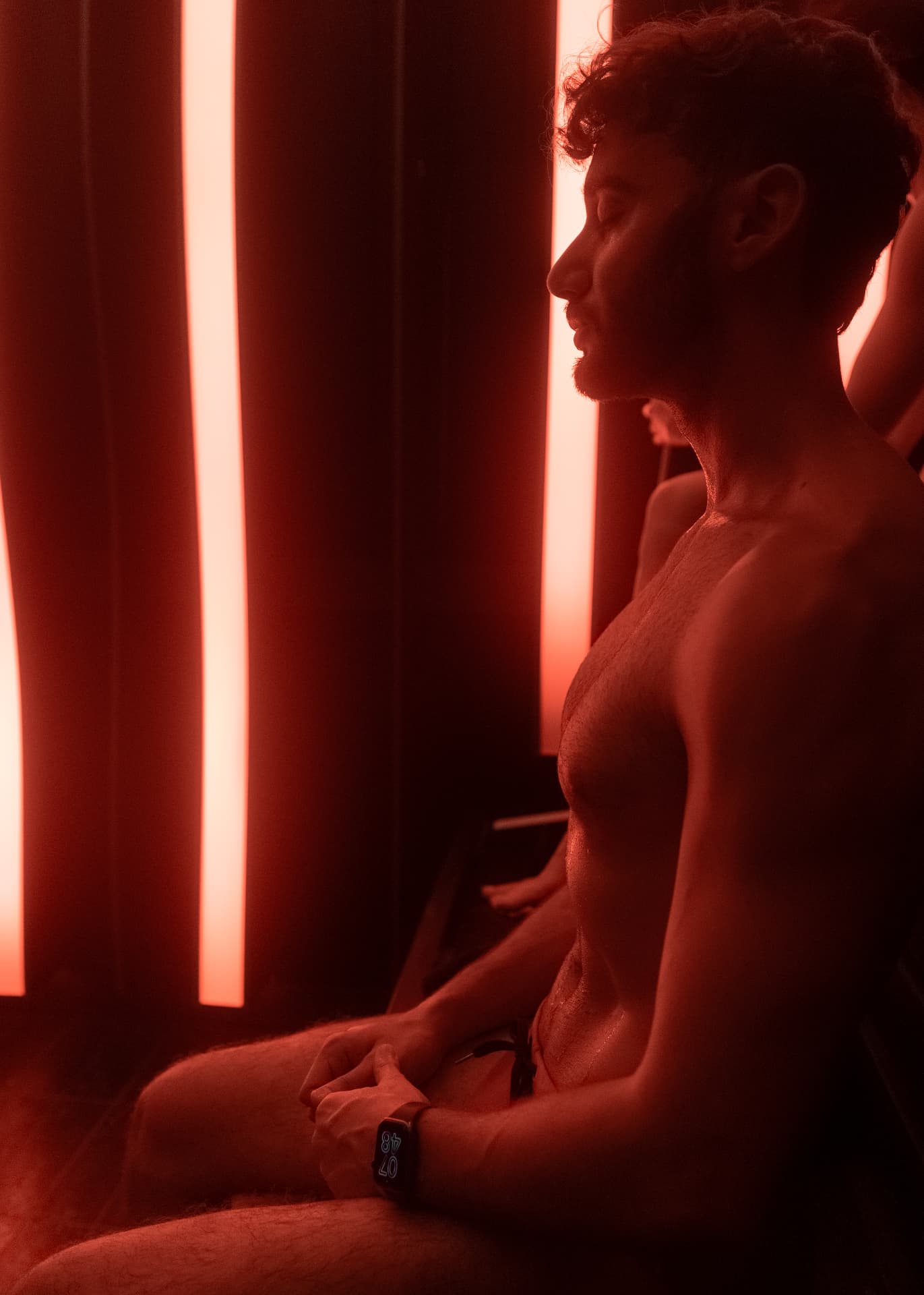 A man in the sauna under red chromotherapy light