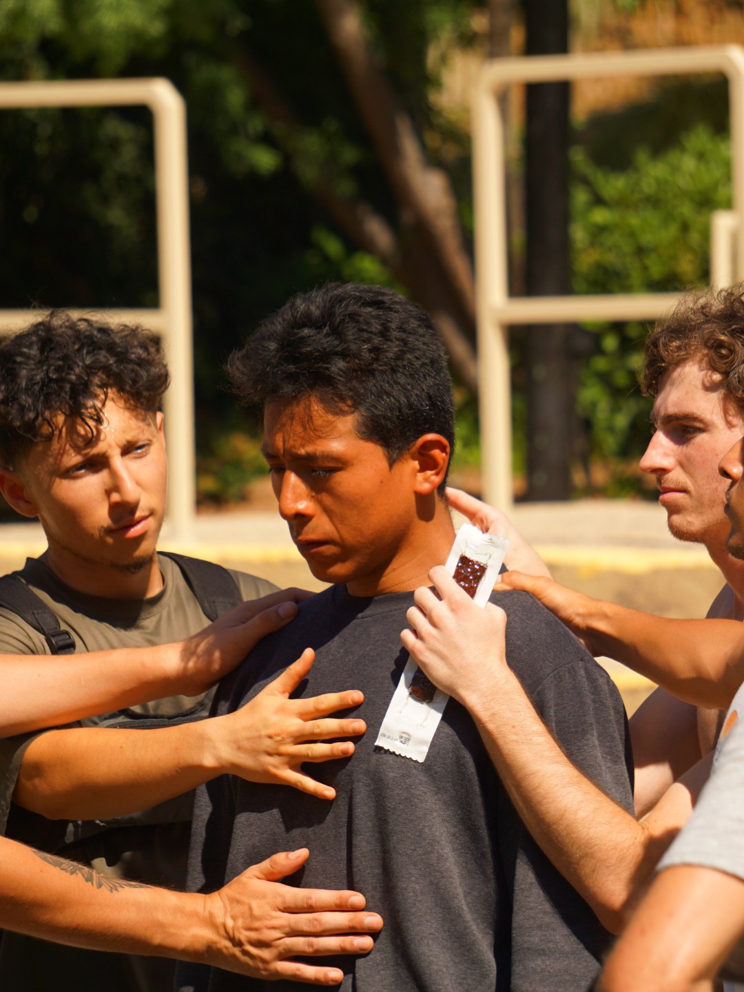 Men placing their hands on a brother in support